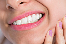 Sonrisa apretando los dientes con dolor